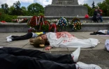 Des manifestants allongés sur le sol, simulent des corps de victimes, pour protester contre l'invasion russe de l'Ukraine, au mausolée des soldats soviétiques à Varsovie, en Pologne, le 9 mai 2025