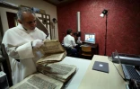 Le père Najeeb Michaeel examine un ancien manuscrit chrétien au Centre de numérisation des manuscrits orientaux (CNMO) à Erbil, dans le nord de l'Irak, le 1er mars 2018