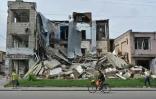 Des habitants passent devant des bâtiments en ruine à Okhtyrka, le 1er août 2022 en Ukraine