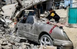 Un garçon soulève des pierres sur une voiture détruite près des décombres d'un immeuble à Rafah, dans le sud de la bande de Gaza, le 5 avril 2024
