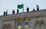 Des Palestiniens mettent un drapeau du mouvement islamiste palestinien Hamas, au pouvoir à Gaza, à l'entrée de la mosquée al-Aqsa sur l'esplanade des Mosquées à Jérusalem, le 10 mai 2021