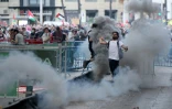 Un homme renvoie une grenade lacrymogène vers la police, après l'invasion des rues par des manifestants propalestiniens pendant la 21e et dernière étape du Tour d'Espagne cycliste, le 14 septembre 2025