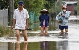Des habitants marchent dans les eaux brunes d'une rivière à Hanoï, inondé après le passage du typhon Yagi, le 12 septembre. 
