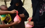 Un homme distribue de l'aide alimentaire à une femme Rohingya à Teknaf au Bangladesh le 12 septembre 2017