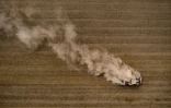 Un tracteur soulève un nuage de poussière en labourant un champ près de Froideville (Suisse), le 26 juillet 2022