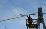 Des techniciens réparent une ligne électrique de trolleybus endommagée à la suite d'une attaque de drone contre le pont du Nord à Kiev, le 3 octobre 2026
