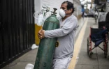 Un homme porte une bouteille d'oxygène pleine destinée à un proche atteint par le coronavirus, le 3 juin 2020 à Lima, au Pérou