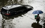 Un homme passe devant uen voiture sous les eaux à Bangkok, où l'état de catastrophe naturelle a été déclaré après des pluies diluviennes qui ont inondé habitations, commerces et axes de circulation, le 27 septembre 2026