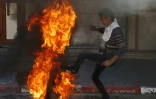 Un manifestant palestinien donne un coup de pied dans un pneu en feu vers des soldats israéliens, le 31 mars 2018 à Hébron, en Cisjordanie