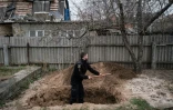 Le policier ukrainien Bogdan Demtsiura exhume le corps d'Andriy Samforskyi, mort à l'âge de 87 ans de maladie le 26 mars 2022 et enterré provisoirement dans son jardin à cause de la guerre, le 19 avril 2022 à Boutcha (Ukraine)