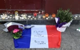 Des bougies, des fleurs et un drapeau français flanqué de la devise de Paris "Fluctuat nec Mergitur" sont déposé près du bar Le Carillon, le 14 novembre 2015