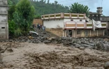 Des villageois (c) près d'un bâtiment alors que le niveau des eaux de crue monte dans le district de Buner, dans la province de Khyber Pakhtunkhwa, le 18 août 2025 au Pakistan