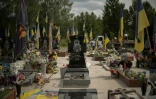 La tombe d'un soldat, entourée de drapeaux aux couleurs ukrainiennes, dans une des allées réservées aux soldats tués au combat contre les forces russes, dans le cimetière de Sumy, dans le nord-est de l'Ukraine, le 11 juin 2025