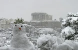 Un bonhomme de neige devant une vue du Parthénon sur l'Acropole recouverte de neige à Athènes le 16 février 2021