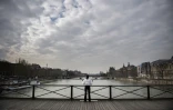 Une femme médite sur le Pont des Arts à Paris le 17 mars 2020, début du premier confinement lié à la pandémie de covid