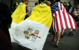 Des Américains avec le drapeau du Vatican et des Etats-Unis quittent l'endroit où le pape François a célébré une messe géante le 27 septembre 2015 à Philadelphie