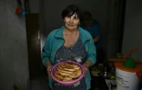 Une habitante tient un plat de galettes de pomme de terre qu'elle a préparées dans un sous-sol servant d'abri, le 30 juin 2022 à Seversk, dans la région de Donetsk, en Ukraine
