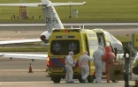 Une personne en combinaison de protection (2e d) escortée vers une ambulance depuis un avion médicalisé transportant des passagers du bateau de croisière MV Hondius, soupçonnés d'être infectés par le hantavirus, à l'aéroport de Schiphol, le 6 mai 2026 près d'Amsterdam, aux Pays-Bas