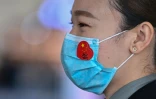 Un employé de l'aéroport de Wuhan porte un masque de protection avec un sticker du drapeau chinois, au jour où s'achève un long bouclage à cause du coronavirus, le 8 avril 2020