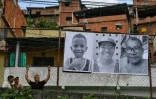 Des passants regardent l'installation de l'exposition de portraits en noir et blanc d'habitants de la communauté de San Blas, dans le cadre du projet artistique mondial "Inside Out" du photographe français JR, dans le quartier de Petare à Caracas, le 12 avril 2022