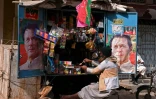 Un vendeur est assis dans son échoppe encadrée par des affiches de l'ancien Premier ministre pakistanais Imran Khan, à Hyderabad, le 29 janvier 2024