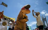 A Manille, le 8 septembre 2018, un manifestant habillé en dinosaure tient une pancarte "Go Fossil-free" ("Finissons-en avec les énergies fossiles"), au cours d'une manifestation dans le cadre de la journée mondiale "Rise for Climate" (Debout pour le climat)
