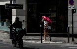Une passante se protège du soleil avec un parapluie dans une rue à Paris, le 13 juillet 2026 lors d'un épisode de canicule en France