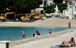 Des engins de chantier draguent du sable pour recharger et agrandir la plage artificielle où des vacanciers prennent le soleil, à Primosten, en Croatie, le 9 mai 2025