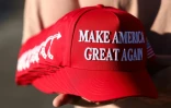 Un membre de Turning Point USA distribue des casquettes "MAGA" aux personnes rassemblées devant un mémorial improvisé en hommage à Charlie Kirk, fondateur de Turning Point USA, devant le siège de l'organisation à Phoenix, en Arizona, le 19 septembre 2025