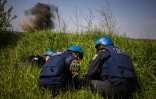 Une équipe de déminage ukranienne s'abrite avant la destruction de restes d'un missile à Hryhorivka (Ukraine) le 5 mai 2022
