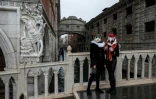 Des artisans vénitiens portant des masques et costumes de carnaval posent près du pont des Soupirs, le 7 février 2021 à Venise (Italie)