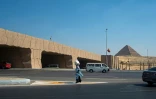 Une femme marche le long d'une route surélevée reliant les pyramides de Guizeh au Grand musée égyptien (GEM) du Caire, le 18 septembre 2025, avant son ouverture officielle