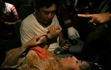 Ye Aung serre la main de son épouse Phyu Lay Khaing dans l'ambulance qui la transporte vers un hôpital, à Mandalay en Birmanie le 29 mars 2025