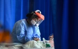 Une soignante réconforte un patient atteint par le coronavirus, le 5 mai 2020 dans un hôpital de Cambridge, au Royaume-Uni