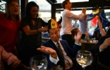 Le politicien britannique Nigel Farage se fait poser un chapeau aux couleurs belges(C), dans une brasserie de Bruxelles lors du match Angleterre-Belgique, le 28 juin 2018 