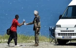 Un voyageur en camping-car donne une bouteille d'eau à un jeune migrant le 12 mai 2021 sur une route menant à Cerbère (Pyrénées-orientales