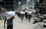 Des Palestiniens portent des sacs de farine à Jabalia, dans le nord de la bande de Gaza, le 1er août 2025

