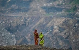 Deux femmes sur les hauteurs d'une mine de charbon à ciel ouvert, à la périphérie de Dhanbad, le 7 juillet 2023 en Inde