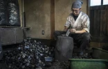 Toru Watanabe, apprenti du forgeron Akihira Kawasaki, casse du charbon de bois dans l'atelier de Kawasaki à Misato, le 9 janvier 2026 au Japon