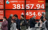 Des piétons passent devant un tableau électronique affichant les chiffres de clôture de la Bourse dans une rue de Tokyo, le 15 février 2024