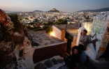 Des touristes profitent de la vue sur Athènes depuis le quartier Anafiotika situé dans la zone archéologique de l'Acropole, le 11 juillet 2018 en Grèce