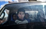Un enfant syrien regarde depuis une voiture des civils en train de fuir la ville d'Afrine dans le nord-est de la Syrie, le 17 mars 2018 