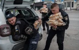 Des policiers chargent du pain destiné à être distribué aux réfugiés de Lyman à Raihorodok, le 2 mai 2022