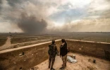 Des membres des Forces démocratiques syriennes (FDS) observent les panaches de fumée après des bombardements sur le dernier réduit du groupe jihadiste Etat islamique (EI) à Baghouz, en Syrie, le 13 mars 2019 