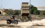 Un couple sur un quad devant un système israélien de défense antimissiles "Dôme de fer" à Askhelon dans le sud du pays, le 7 août 2022 