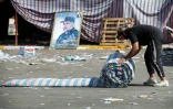 Un partisan du leader chiite Moqtada Sadr roule un matelas lors du démantèlement d'un campement dans la Zone verte, le 30 août 2022 à Bagdad, en Irak