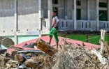 Un enfant debout sur des débris d'arbres après des crues soudaines à Meureudu, dans province d'Aceh, en Indonésie, le 8 décembre 2025