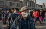 Des Chinois, un masque de protection sur le visage, arrivent à la gare de Pékin pour prendre un train et rendre visite à leurs familles à l'occasion des congés du Nouvel An, le 21 janvier 2020 en Chine