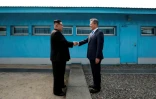 Moon Jae-in (d) et Kim Jong Un se serrent la main sur la ligne de démarcation avant le début du sommet, le 27 avril 2018 à Panmunjom