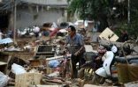 Un habitant pousse son vélo au milieu des débris dans une zone inondée après la rupture d'un réservoir près de Gantang, dans la région du Guangxi, le 9 juillet 2026 dans le sud-ouest de la Chine